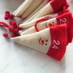 Adventskalender aus Filzmützen mit stilisiertem Schneemann-Gesicht