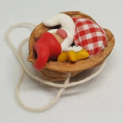 Baumschmuck Walnussschale Schaukelbettchen mit kleinem schlafend Wichtel mit roter Zipfelmütze und kleinem Stern