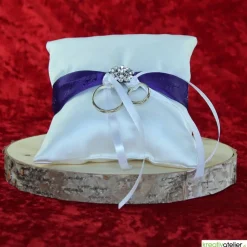 Elegantes Ringkissen aus weißem Satin mit lilanem Satinband und zarter weißer Schleife - Perfekte Hochzeitsdekoration