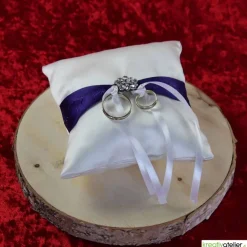 Elegantes Ringkissen aus weißem Satin mit lilanem Satinband und zarter weißer Schleife - Perfekte Hochzeitsdekoration