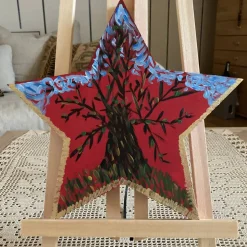 Festlicher Holzstern, winterlicher Baum und Himmel, bemalter und verzierter Holzstern