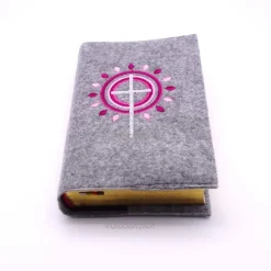 Gotteslobhülle, Filz, grau, bestickt mit grauem Kreuz, rosa + dunkelroten Strahen, die wie eine Blume angeordnet sind