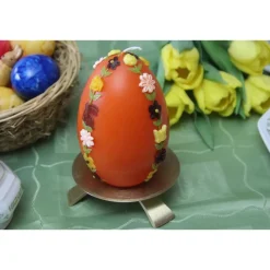große Ostereikerze in orange mit doppelter, frühlingshafter Blumenranke verziert, Osterdeko, Ostergeschenk