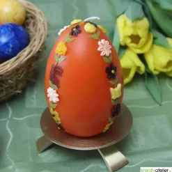 große Ostereikerze in orange mit doppelter, frühlingshafter Blumenranke verziert, Osterdeko, Ostergeschenk
