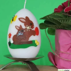 große Ostereikerze in weiß mit Hasenmutter, Hasenkind und bunten Ostereiern verziert, Osterdeko, Ostergeschenk