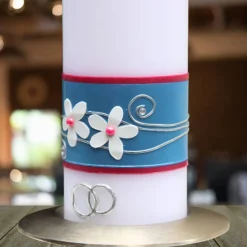Hochzeitskerze mit blauem Band, weißen Blumen und silbernen Ringen, personalisierbar, stilvolle Hochzeitsdeko