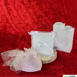 Liebevoll gefertigtes Ringkissen aus zartem Häkelstoff in reinweißer Farbe mit verspielten Herzchen und Satinschleifen