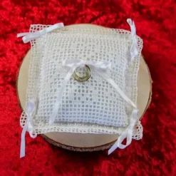 Liebevoll gefertigtes Ringkissen aus zartem Häkelstoff in reinweißer Farbe mit verspielten Herzchen und Satinschleifen