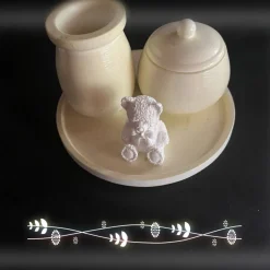 Set aus Teddy, Töpfchen und kleiner Vase auf einem runden Tablett