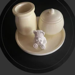 Set aus Teddy, Töpfchen und kleiner Vase auf einem runden Tablett