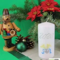 Weiße Silvesterkerze mit Jahreszahl und Sektgläsern