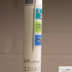 weiße Taufkerze mit Kreuz und den Symbolen Taube, Alpha und Omega, Wellen, Fisch auf 4 farbigen Kacheln