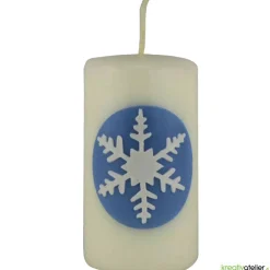 Zauberhaftes Lichtspiel für die Wintermonate: Winterkerze mit Eiskristall / Schneeflocke auf blauem Himmel