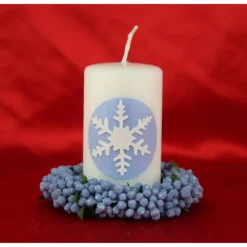 Zauberhaftes Lichtspiel für die Wintermonate: Winterkerze mit Eiskristall / Schneeflocke auf blauem Himmel